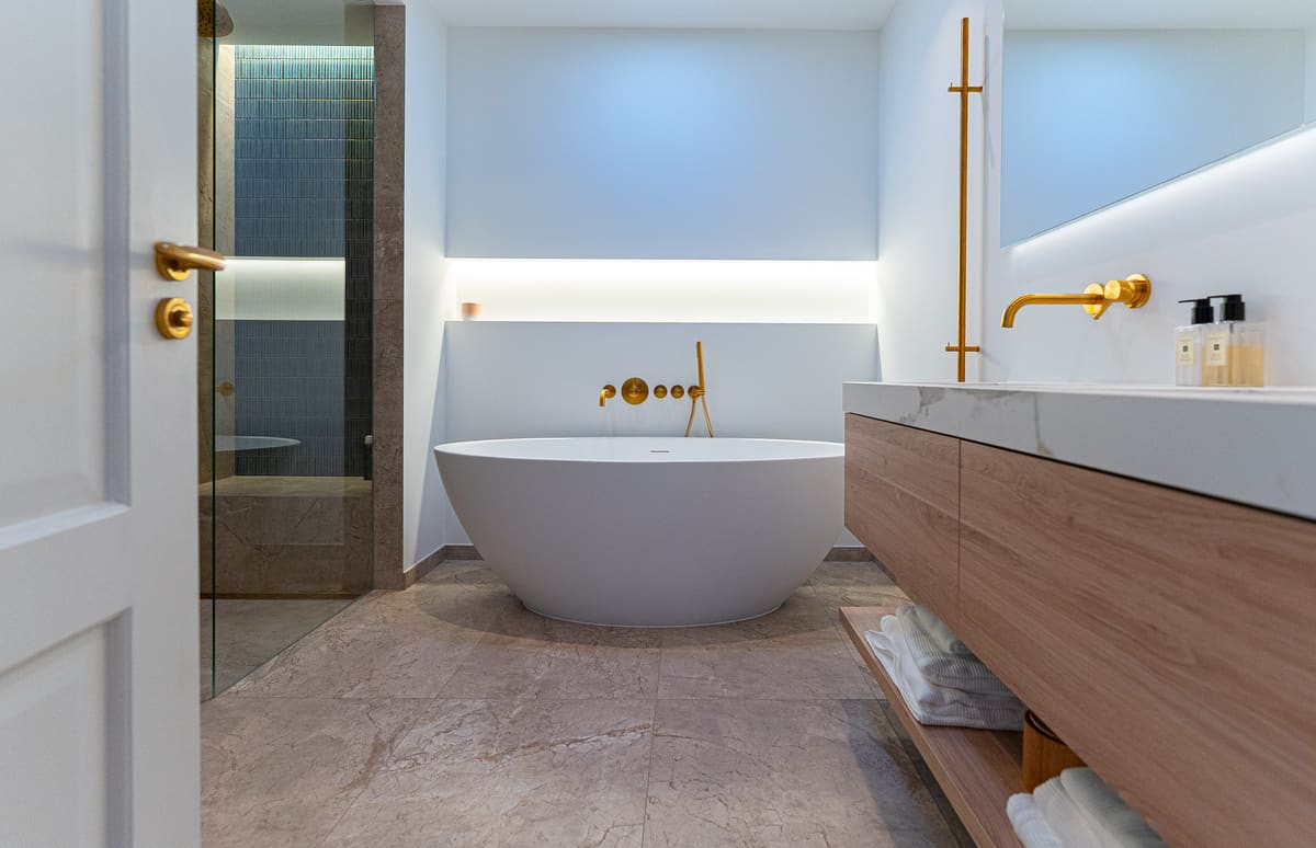 Luxe badkamer met vrijstaand bad, marmerlook en kranen in geborsteld messing